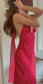 Woman wearing a red polka dot dress with sheer sides in a room.