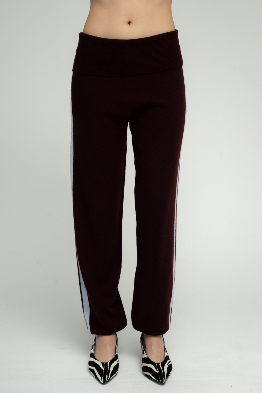 Dark burgundy knit wide-leg pants with light blue side stripes and fold-over waistband, styled with zebra print heels.