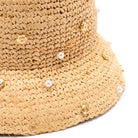 Beige straw hat with pearl and gold bead embellishments on a white background