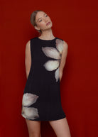 Black sleeveless mini dress with abstract white petal print and textured pleated fabric