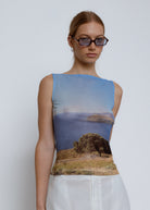Sleeveless mesh top with scenic landscape print featuring blue sky, ocean, and lone tree on coastal hillside