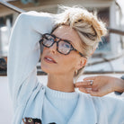 Woman wearing glasses and a light blue sweater with a blurred background