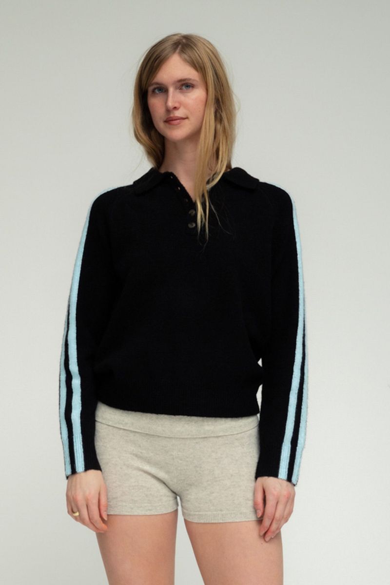 Black knit polo sweater with light blue side stripes, button collar, worn with gray mini shorts.
