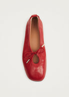 Red leather ballet flat by Alohas with gold-tipped bow detail, square toe, and tan leather insole.
