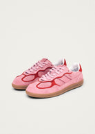 Pink suede sneakers with red accent trim, gum sole, and white heel tab in classic low-top silhouette
