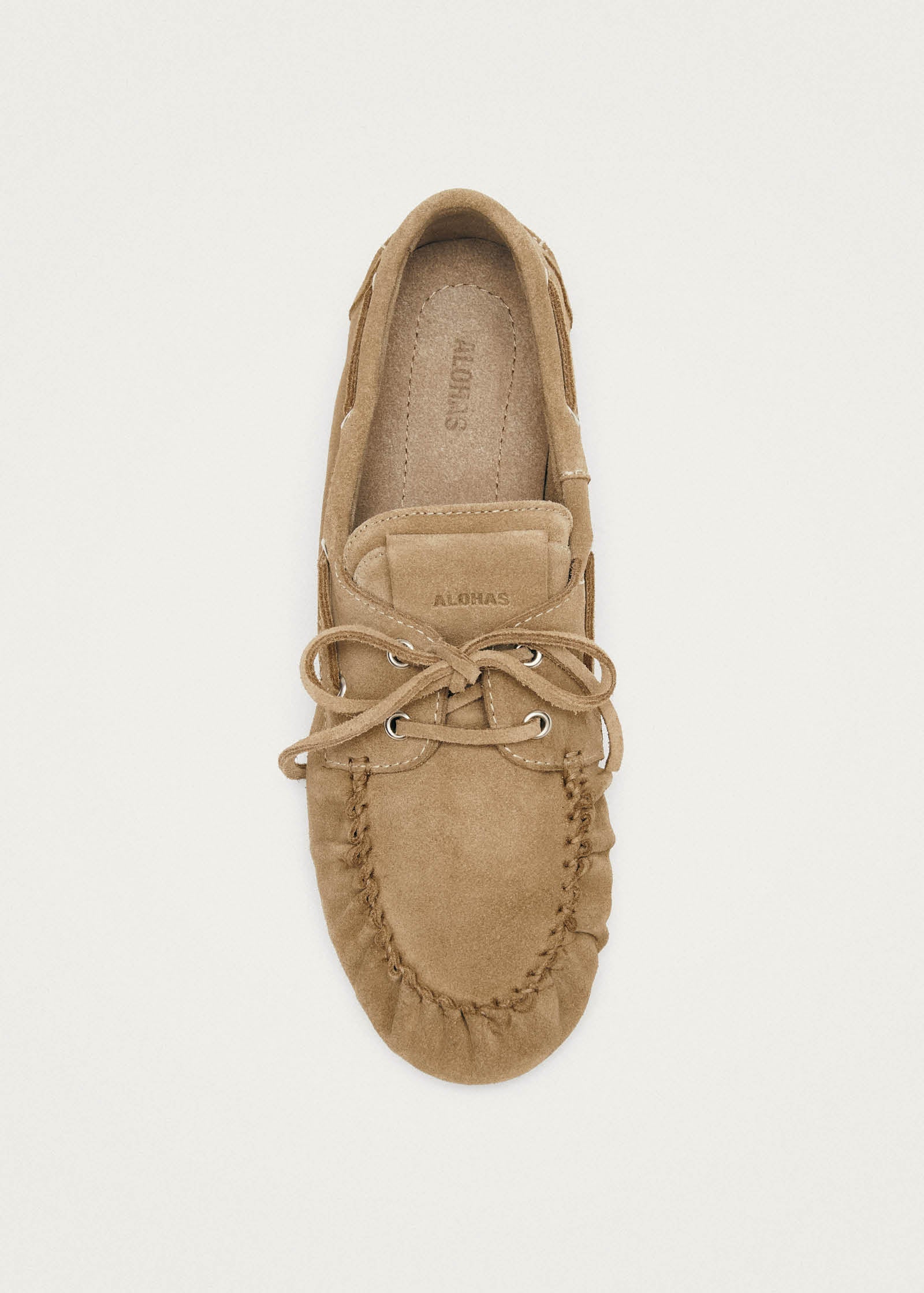 Tan suede moccasin slipper with lace-up detail and ALOHAS branding, viewed from above on beige background