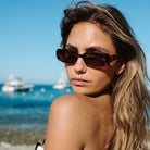 Woman wearing sunglasses with a beach and ocean background