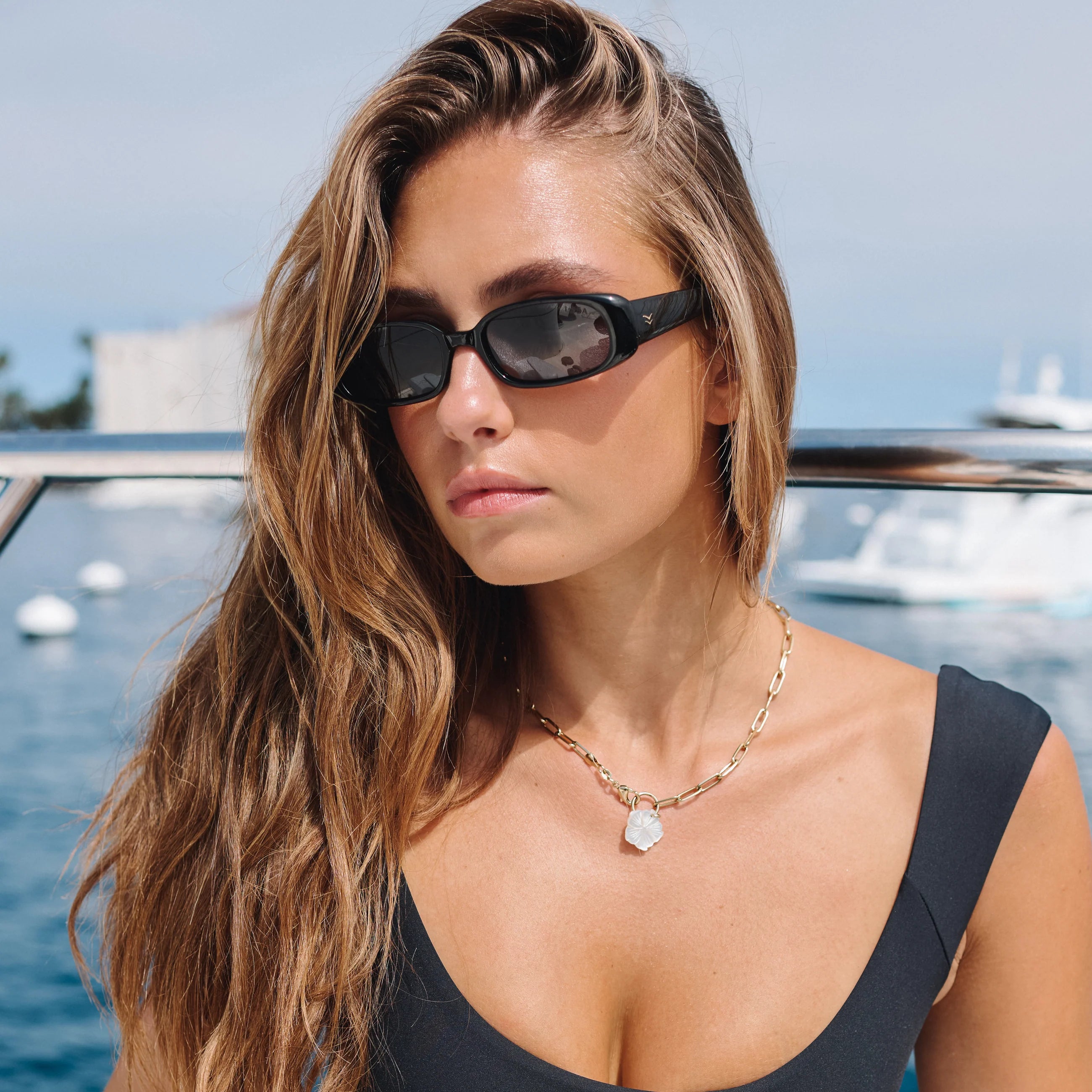 Woman wearing sunglasses with a boat and water in the background