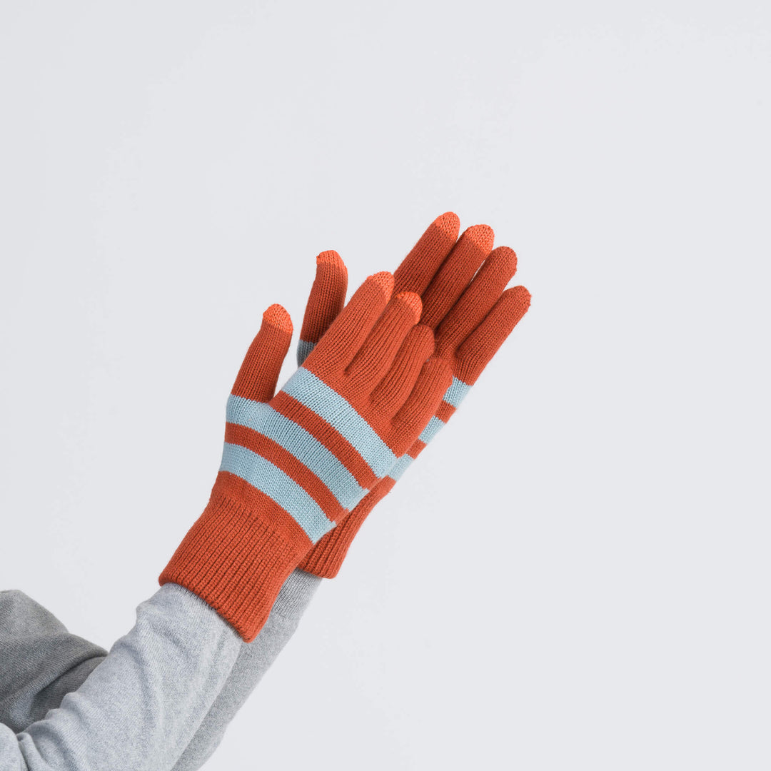 Orange and light blue striped knit gloves with ribbed texture and extended cuffs displayed on raised hand