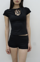 Black fitted crop top with keyhole cutout and tie detail at neckline, paired with black shorts