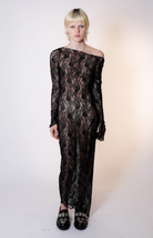 Black lace off-shoulder maxi dress with long sleeves and sheer floral pattern, worn with embellished loafers