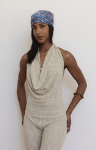 Woman wearing cream textured halter top with cowl neck and matching pants, styled with blue patterned headband