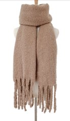 Beige knit scarf with fringe tassels displayed on mannequin stand against white background