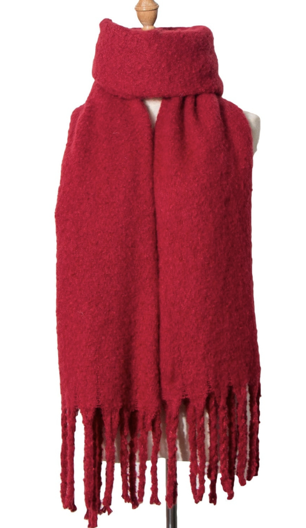 Red knit scarf with fringe detail displayed on wooden dress form mannequin against white background