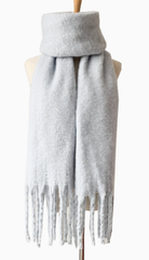 Light gray knit scarf with fringe detail draped on dress form mannequin