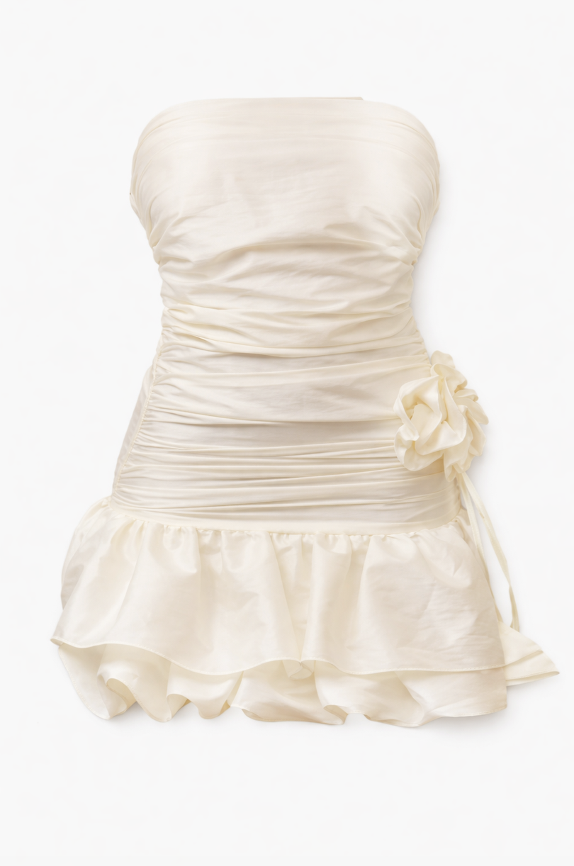 Ivory strapless mini dress with ruched bodice, gathered waist with flower detail, and ruffled tiered skirt hem