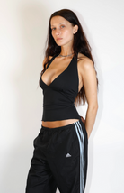 Black halter wrap top with deep V-neckline paired with black Adidas track pants with white stripes