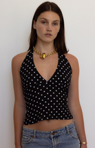 Black polka dot halter top with white dots, V-neck silhouette, cropped length, modeled with gold chain necklace and jeans
