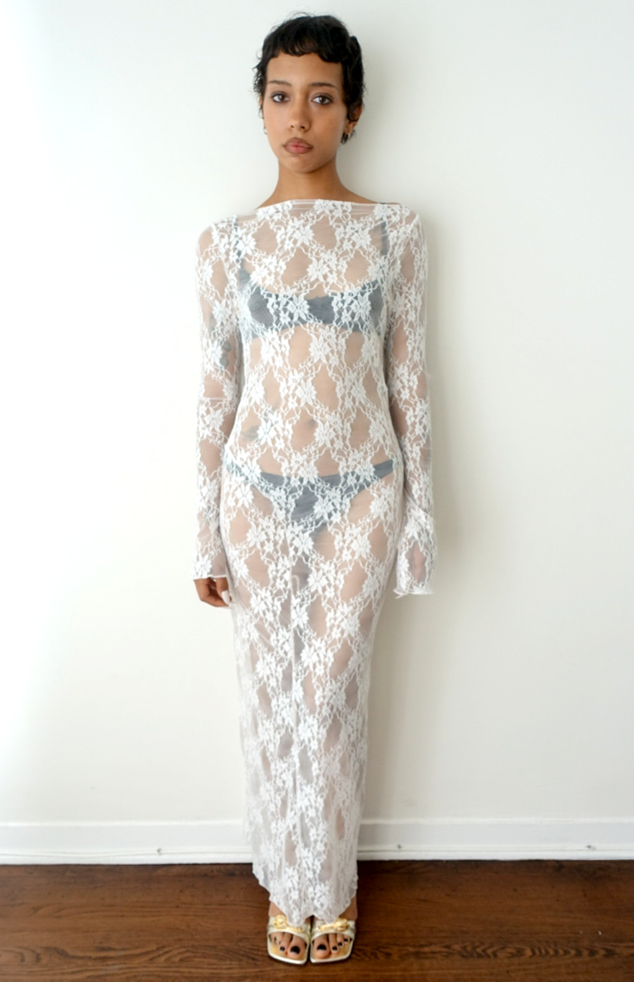 White lace long sleeve maxi dress with sheer overlay and boat neckline, worn with gray undergarments and gold sandals