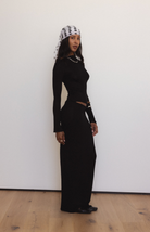 Woman wearing black long-sleeve cutout maxi dress with chain detail neckline and white patterned headscarf
