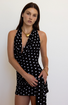 Black polka dot halter dress with plunging neckline and draped fabric detail, styled with gold heart necklace
