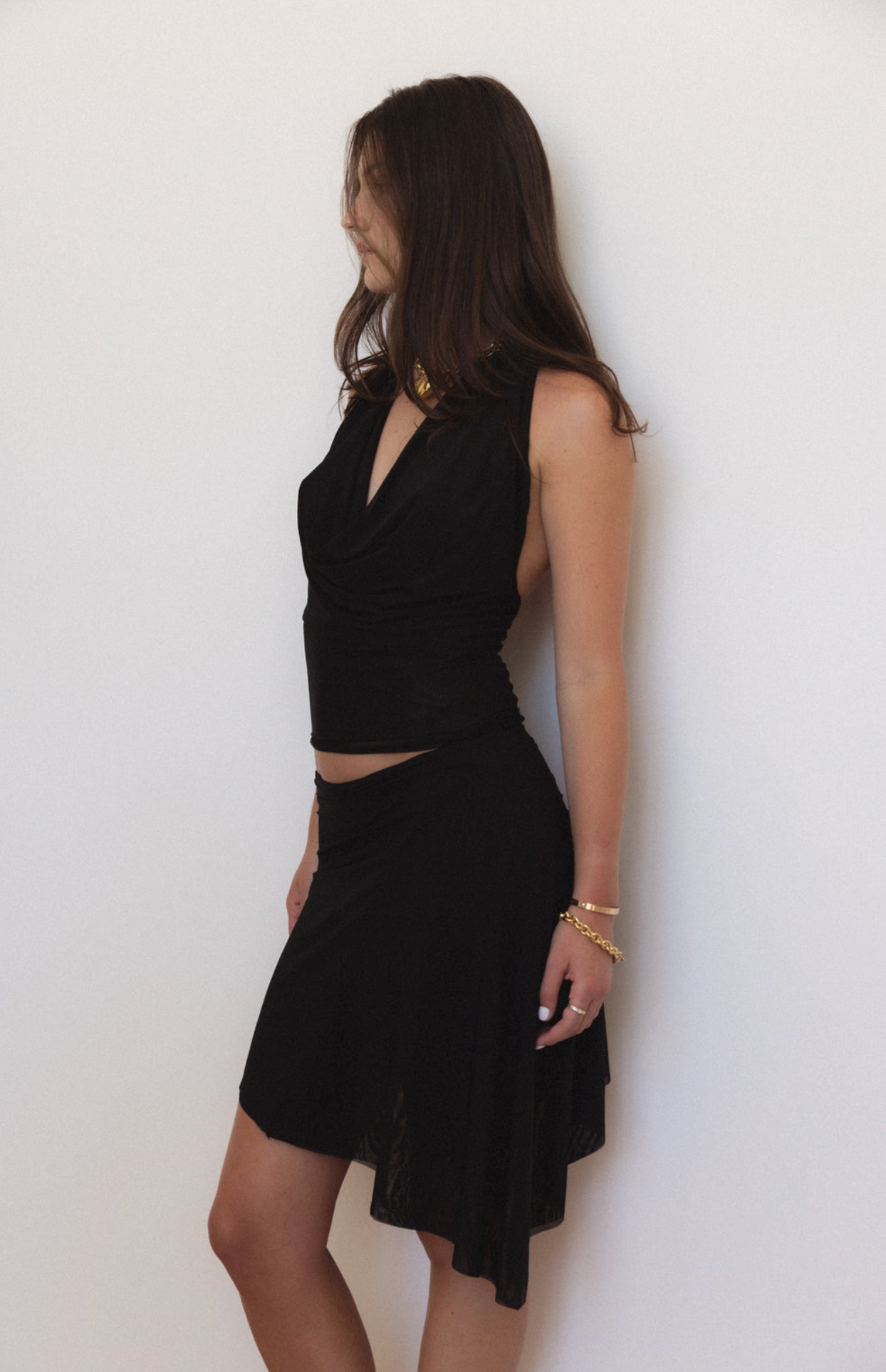 Black sleeveless two-piece set with cropped top and asymmetrical mini skirt in textured fabric