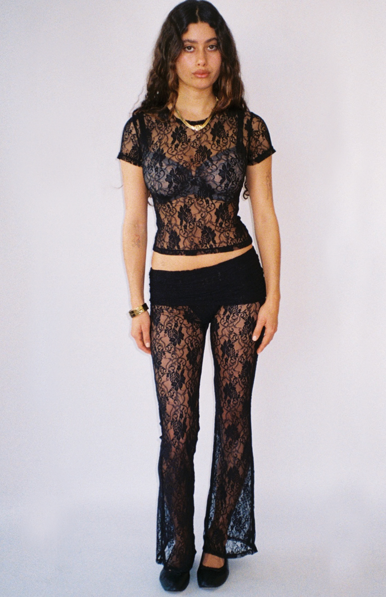 Black lace two-piece set with short-sleeve crop top and flared pants, sheer overlay design with solid underlay