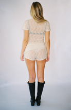 Cream lace shorts and top set shown from back, paired with black knee-high boots on model with blonde hair