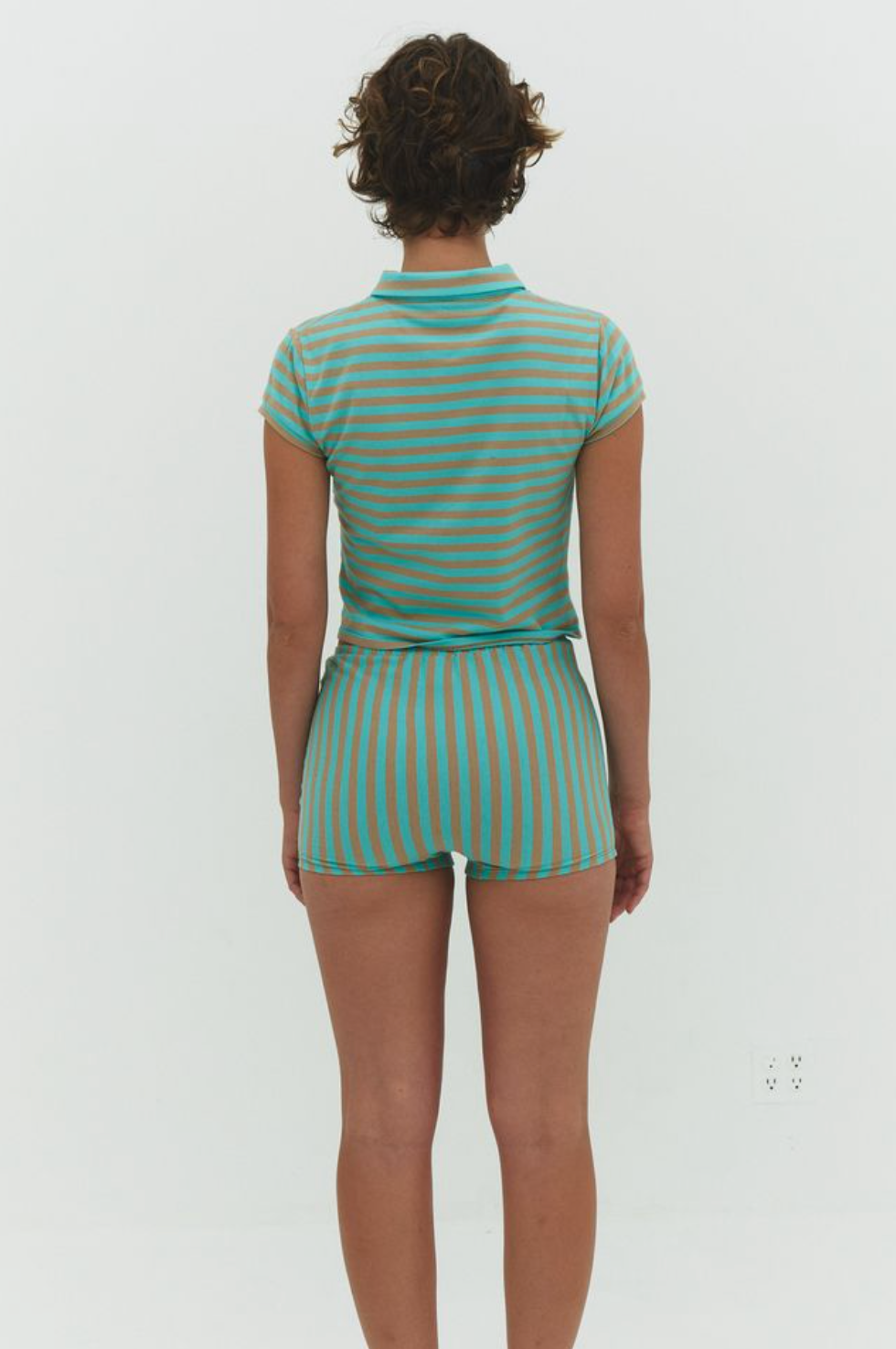 Back view of person wearing turquoise and tan striped polo shirt and matching shorts set in ribbed knit fabric