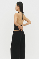 Black halter backless top with tie neck and wide-leg pants set, showing open back design from side view