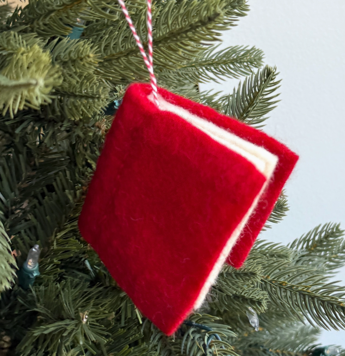 Red velvet mini stocking ornament with white trim hanging on evergreen Christmas tree branches