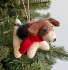 Felted wool beagle dog Christmas ornament with brown, black and cream coloring wearing red scarf hanging on evergreen tree