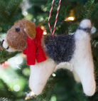 Felt beagle dog Christmas ornament with brown, black and white coloring wearing red scarf hanging on evergreen tree