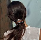 Dark tortoiseshell hair barrette with floral embellishment holding back long brown hair in a ponytail