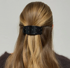 Black studded hair barrette clip holding back blonde hair in half-up style