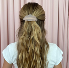 Translucent white cloud-shaped hair clip with pearl beads securing half-up hairstyle on long blonde wavy hair