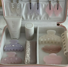 Pink and white travel jewelry and beauty organizer case with hair clips, styling cream, and decorative hair accessories