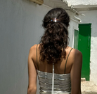 Rose gold crystal hair clip holding back curly dark hair in half-up style