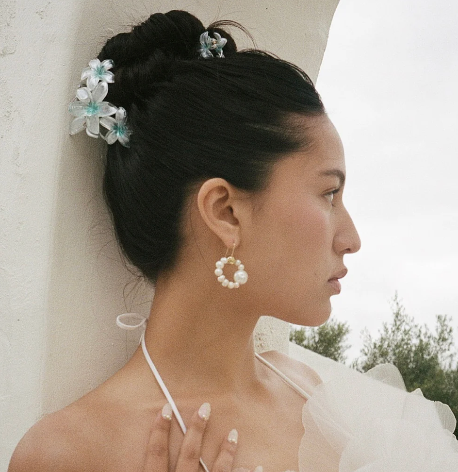 White pearl circular hoop earrings with gold accent, worn with an updo hairstyle and floral hair accessories
