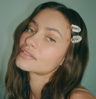 White resin hair clips with gold hardware and blue floral detail, worn by model with brown hair