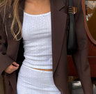 Brown oversized blazer worn over white eyelet lace matching set with crop top and skirt