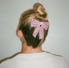Pink velvet hair bow with rhinestone center on blonde bun hairstyle
