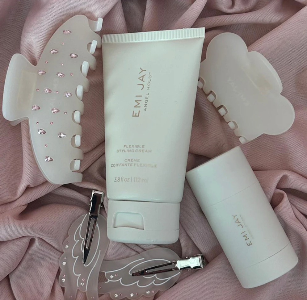 Emi Jay Angel Hold flexible styling cream tube with hair tools and claw clips on pink fabric background