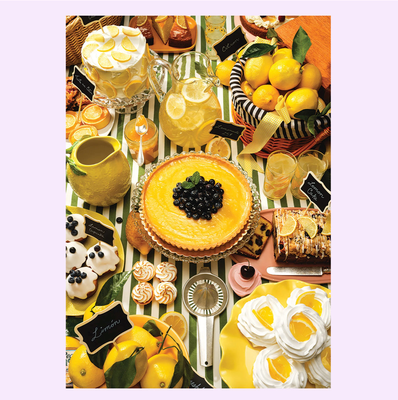 Lemon-themed dessert table with yellow tart, cakes, cookies, lemonade pitchers, and fresh lemons on striped tablecloth