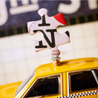 Puzzle piece decoration mounted on yellow toy taxi cab roof, featuring black letters and red accent detail