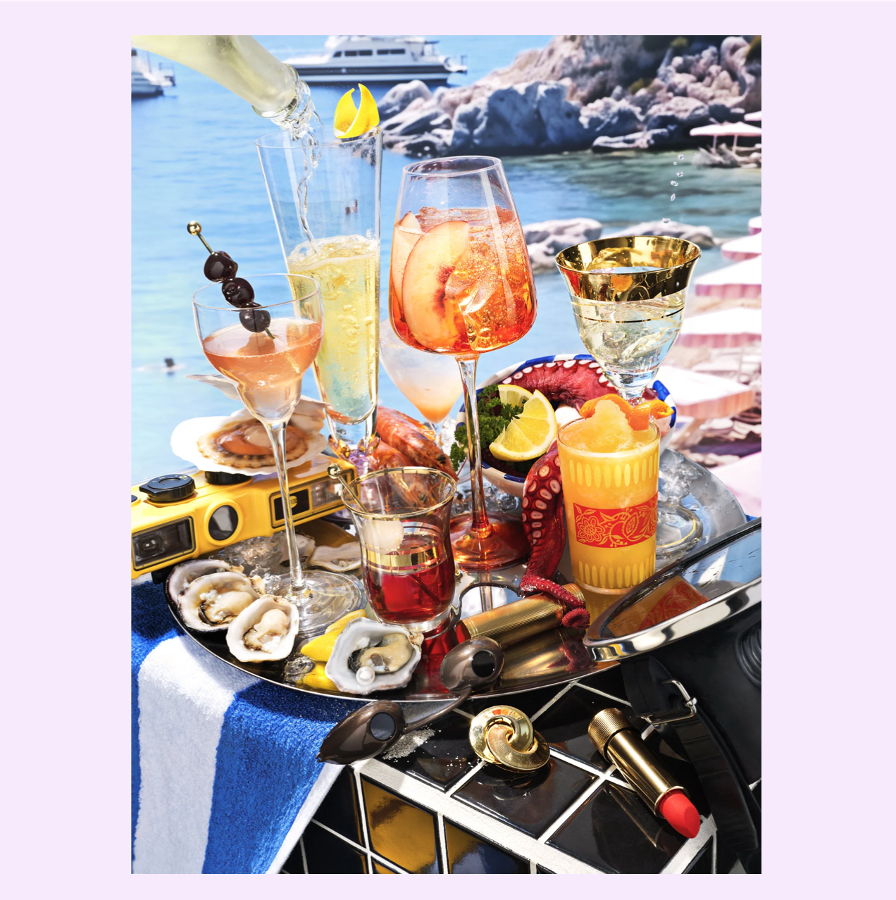 Colorful cocktails and seafood on metal tray with coastal Mediterranean backdrop, featuring wine glasses, oysters, and bar tools