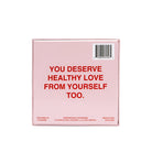 Pink game box with red text reading "YOU DESERVE HEALTHY LOVE FROM YOURSELF TOO" and barcode on top