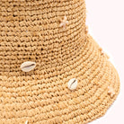 Close-up of a woven straw hat with starfish and shells on a white background