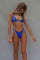 Cobalt blue two-piece bikini set with strappy triangle top and high-cut bottoms on model against grey background