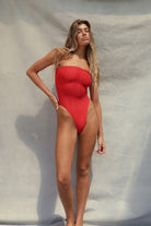 Woman wearing a red strapless swimsuit against a neutral background
